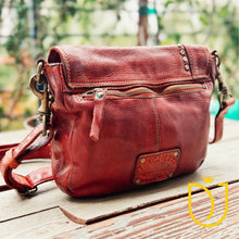 Load image into Gallery viewer, Angled back view of the Washoe Lake brick-red leather crossbody showing zip pocket and brass clasp hardware