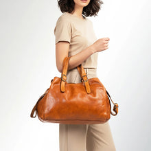 Load image into Gallery viewer, Model carrying the Avalon tan Italian leather shoulder tote with buckled straps over her arm
