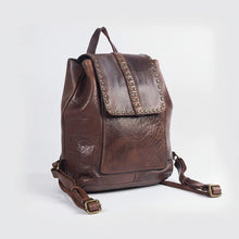 Load image into Gallery viewer, Angled view of the Sawyer brown pebbled leather backpack with studded flap and adjustable leather straps
