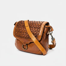 Load image into Gallery viewer, Three-quarter view of the Lucca cognac woven leather crossbody with brass ring accent and detachable strap