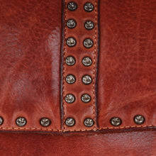 Load image into Gallery viewer, Close-up of the star-embossed studs and stitched center stripe on the Sawyer cognac leather backpack flap