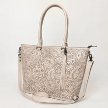 Load image into Gallery viewer, Maple Creek hand tooled leather concealed carry tote in white, angled view showing floral tooling, tassel and strap