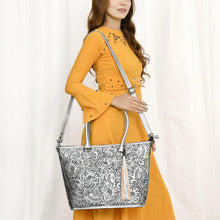 Load image into Gallery viewer, Model wearing the Maple Creek hand tooled leather concealed carry tote in silver over the shoulder on its detachable strap