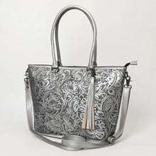 Load image into Gallery viewer, Maple Creek hand tooled leather concealed carry tote in metallic silver, angled view showing floral tooling, tassel and strap