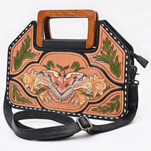 Load image into Gallery viewer, Angled view of the Moonflower hand tooled leather crossbody purse showing the black side gusset and swivel strap clips