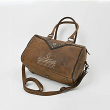 Load image into Gallery viewer, Bowie western satchel viewed from above at an angle, showing the top zip closure, studded front yoke, and the protective metal feet on the base