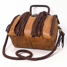 Load image into Gallery viewer, Reata leather barrel satchel in Honey Tan, angled view of the base with antique brass feet and braided crossbody strap