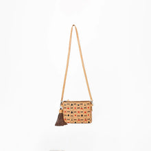 Load image into Gallery viewer, A small crossbody bag with a tan leather strap and a patterned body featuring a beige background with small red, black, and green motifs. It has a dark brown tassel hanging from the front.