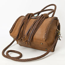 Load image into Gallery viewer, Reata leather barrel satchel in Caramel, angled view of the base with antique brass feet and braided crossbody strap