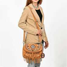 Load image into Gallery viewer, Model wearing the Lodestar embroidered suede fringe crossbody with a tan blazer and turquoise jewelry