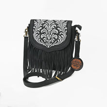 Load image into Gallery viewer, Raven black leather crossbody bag with white scroll embroidery on the flap and long leather fringe, three-quarter view