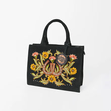 Load image into Gallery viewer, Lady Luck black suede tote with embroidered horseshoes and sunflowers, angled view