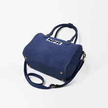 Load image into Gallery viewer, Lockhart navy suede Western speedy bag with NFR embroidered patch and rolled handles. A navy blue suede handbag with a top handle, a detachable shoulder strap, and a white 'NFR' logo patch on the front, set against a plain white background.