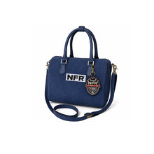 Load image into Gallery viewer, Lockhart navy suede Western speedy bag with NFR embroidered patch and rolled handles. A navy blue faux-leather handbag with dual top handles, a detachable shoulder strap, and gold-tone hardware. The front features a white rectangular patch with 'NFR' in black letters and a hanging shield-shaped 'NFR' charm.
