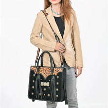 Load image into Gallery viewer, Woman wearing the Fandango hair-on leather fringe tote crossbody on its hand-tooled strap with a camel blazer and turquoise jewelry