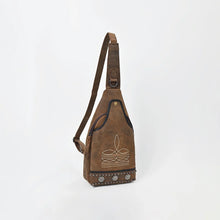 Load image into Gallery viewer, Austin western sling bag in distressed brown genuine leather, angled side view showing the adjustable strap with D-ring, cream stitched sprig motif on the front slip pocket, and studded hem