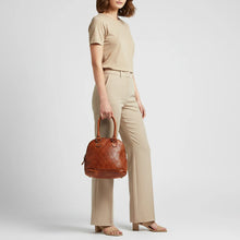 Load image into Gallery viewer, Model carrying the Harley diamond quilted Italian leather dome satchel in cognac by its top handles

