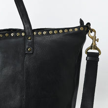 Load image into Gallery viewer, Close-up of the Emmylou black tote showing a row of star-head antique brass studs along the topline and a brass swivel strap clip
