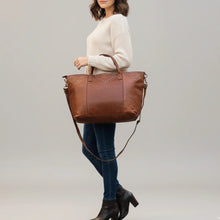 Load image into Gallery viewer, Model in a cream sweater carrying the Emmylou studded Italian leather tote in cognac on her forearm, with the crossbody strap below
