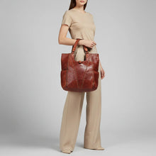 Load image into Gallery viewer, Model carrying the Sedona cognac-red Italian leather studded slouch tote over her arm

