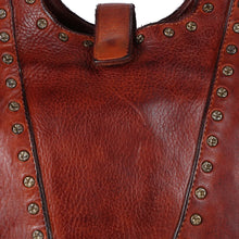 Load image into Gallery viewer, Close-up of Sedona cognac-red Italian leather with star-stamped antique brass rivets and snap tab

