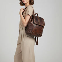 Load image into Gallery viewer, Woman wearing the Sawyer brown studded leather backpack over one shoulder
