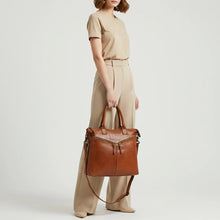 Load image into Gallery viewer, Model carrying the Vivienne cognac Italian leather zip tote by its top handles with crossbody strap
