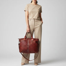 Load image into Gallery viewer, Model carrying the Penelope oxblood woven Italian leather tote by its top handles
