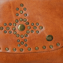 Load image into Gallery viewer, Close-up of the Estrella tan leather flap showing the star-and-cross medallion of antique-brass-tone studs and snap buttons

