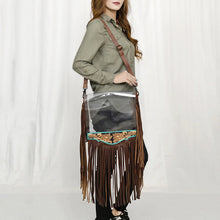 Load image into Gallery viewer, Woman wearing the Curtain Call clear crossbody purse with long leather fringe and turquoise-trimmed tooled panel

