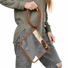 Load image into Gallery viewer, Gold Dust clear wristlet clutch held by its leather bangle loop, cowhide band at top
