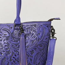 Load image into Gallery viewer, Close-up of Maple Creek purple tote showing hand-tooled florals, fringe tassel and antique brass swivel clip

