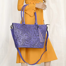 Load image into Gallery viewer, Model wearing the Maple Creek hand tooled leather tote in purple
