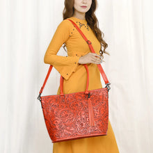 Load image into Gallery viewer, Model wearing the Maple Creek hand tooled leather concealed carry tote in red
