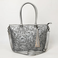 Load image into Gallery viewer, Maple Creek hand tooled leather concealed carry tote in metallic silver, front view with antiqued floral tooling, fringe tassel and strap
