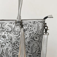 Load image into Gallery viewer, Close-up of Maple Creek silver tote showing antiqued hand-tooled florals, fringe tassel and antique brass swivel clip
