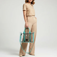 Load image into Gallery viewer, Woman holding the Turquoise Trail clear tote by its turquoise leather handles, crossbody strap hanging
