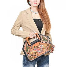 Load image into Gallery viewer, Model carrying the Moonflower hand tooled leather purse by its wooden top handle with turquoise jewelry
