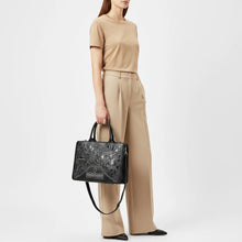 Load image into Gallery viewer, Model holding the Sable black leather western cutout tote bag with silver studs and braided edges
