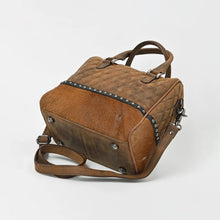 Load image into Gallery viewer, Base of the Buckskin satchel showing hair-on cowhide and protective metal feet
