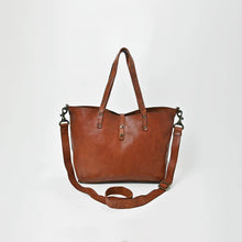 Load image into Gallery viewer, Amber riveted leather crossbody tote in cognac, front view with brass-riveted handles, snap tab closure and adjustable strap
