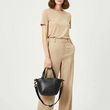 Load image into Gallery viewer, Model carrying the Riva black Italian leather riveted mini tote by the top handles
