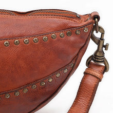 Load image into Gallery viewer, Close-up of Comet star-stamped antique brass studs, zipper and swivel clip on cognac leather
