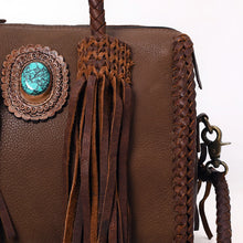 Load image into Gallery viewer, Close-up of the Reata satchel in Chocolate: turquoise stone in a tooled leather rosette, braided fringe tassel, and antique brass clasp
