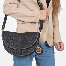 Load image into Gallery viewer, Nightshade black embossed suede saddle bag worn crossbody, close view
