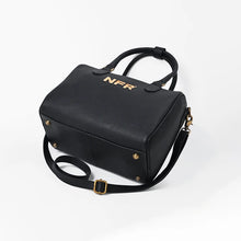 Load image into Gallery viewer, A black textured faux-leather handbag with gold hardware and a gold 'NFR' logo on the front, shown on a clean white background.
