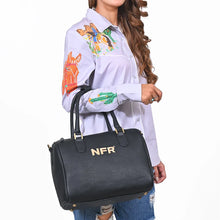 Load image into Gallery viewer, A woman wearing a light lavender embroidered shirt and ripped blue jeans carries a black pebbled faux-leather tote bag with gold hardware and the brand name 'NFR' printed in gold on the front.
