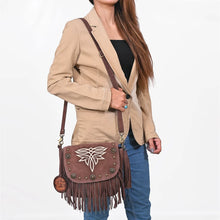 Load image into Gallery viewer, Woman wearing the brown Sparrow suede fringe crossbody purse with a camel blazer and jeans
