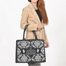 Load image into Gallery viewer, Woman carrying the Lacey black and white embroidered leather tote on her forearm, styled with a camel blazer and turquoise necklace

