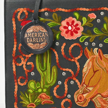 Load image into Gallery viewer, Close-up of the Liberty tote's chain-stitch embroidery: golden horse head, saguaro cactus, pink flower, lariat loops, and rhinestone studs on black leather
